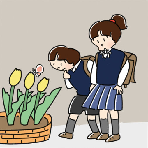 黄色いチューリップの上を飛ぶちょうちょを見つけた小学生